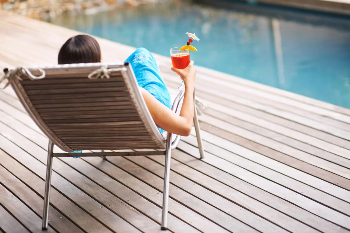 a woman enjoying a drink on the pool deck