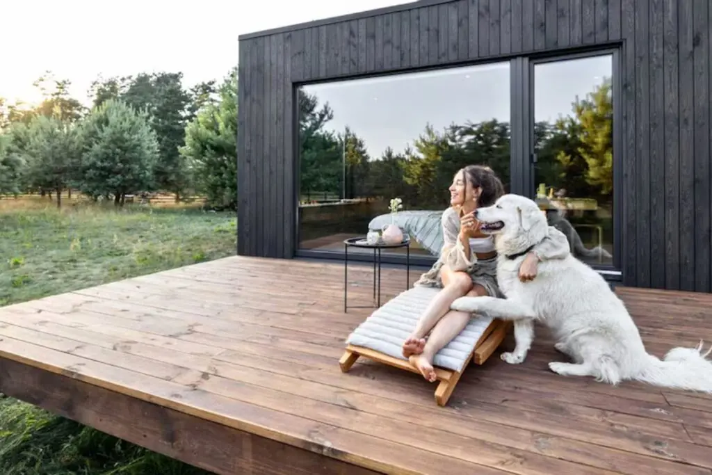 woman and dog in backyard wooden deck enjoying the natures beauty