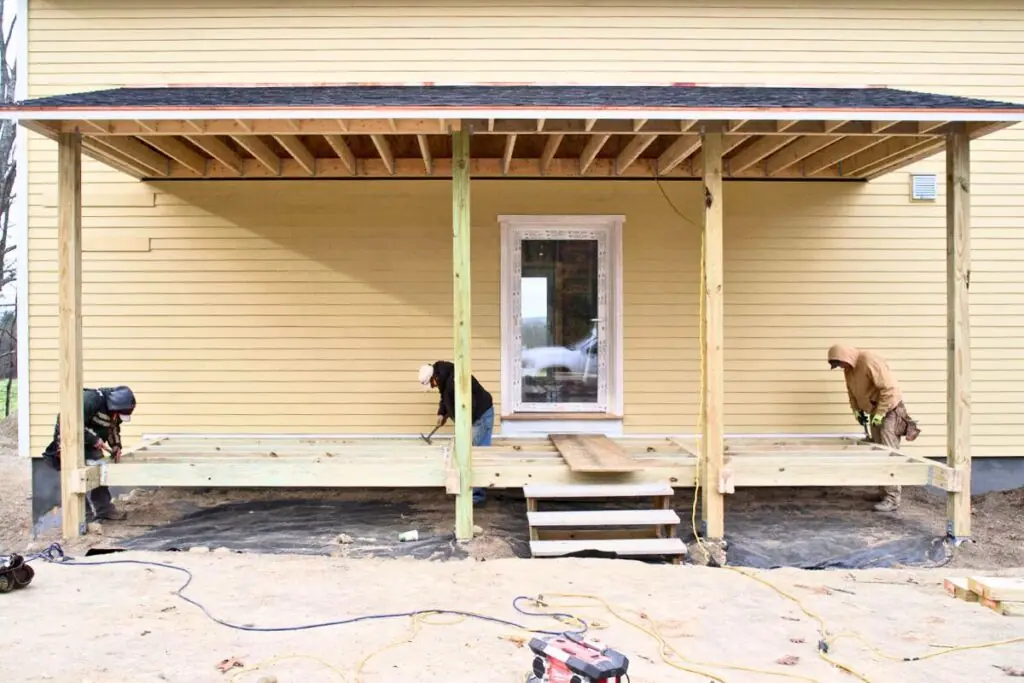 three contractors renovating old wooden porch