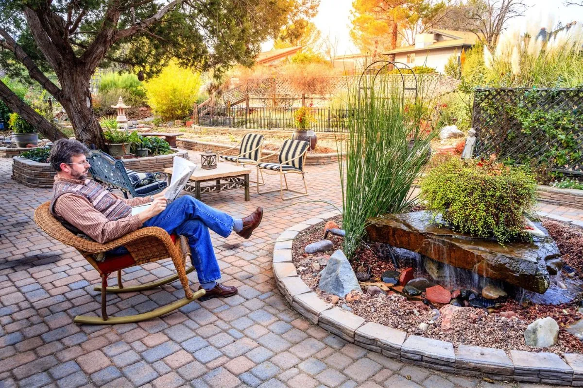 old man reading newspaper in hardscape patio